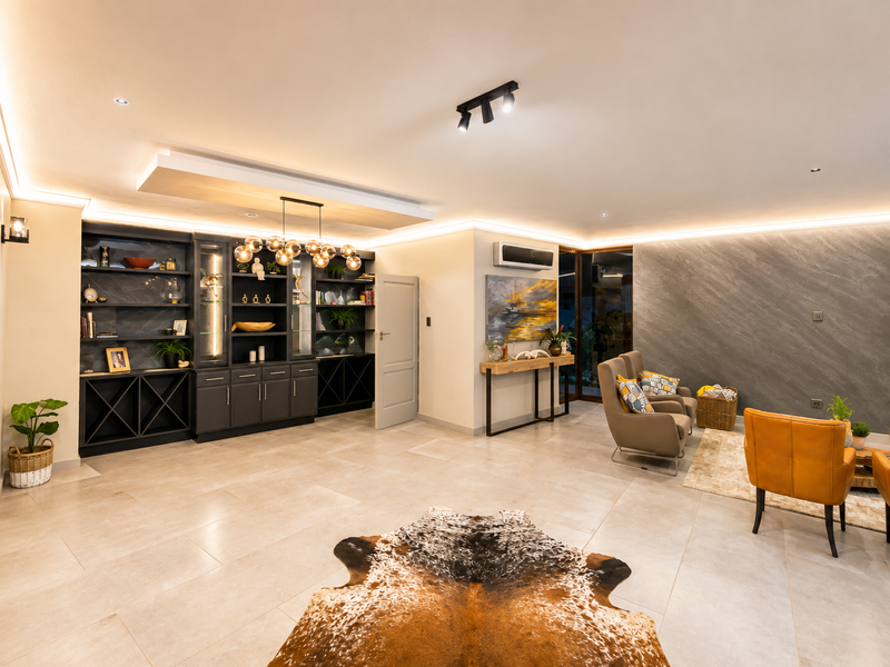 Spacious living area featuring modern built-in cabinetry, elegant cove and recessed lighting, split-system air conditioning, and high-quality tiled flooring.