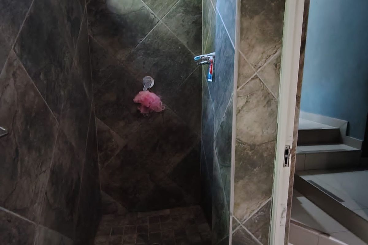 A compact shower enclosure featuring dark stone-look wall and floor tiles, providing a functional and modern aesthetic.