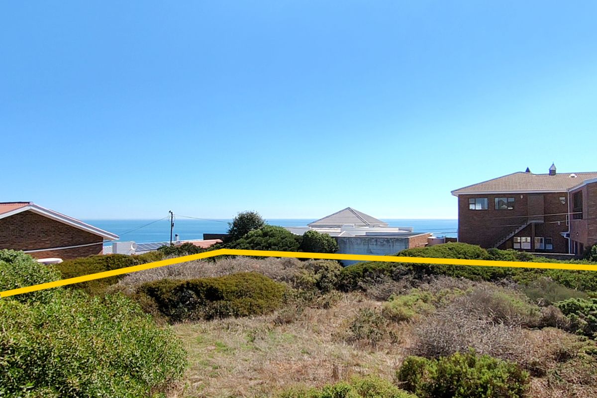 A vacant residential plot featuring coastal views, surrounded by established residential properties and natural coastal vegetation.