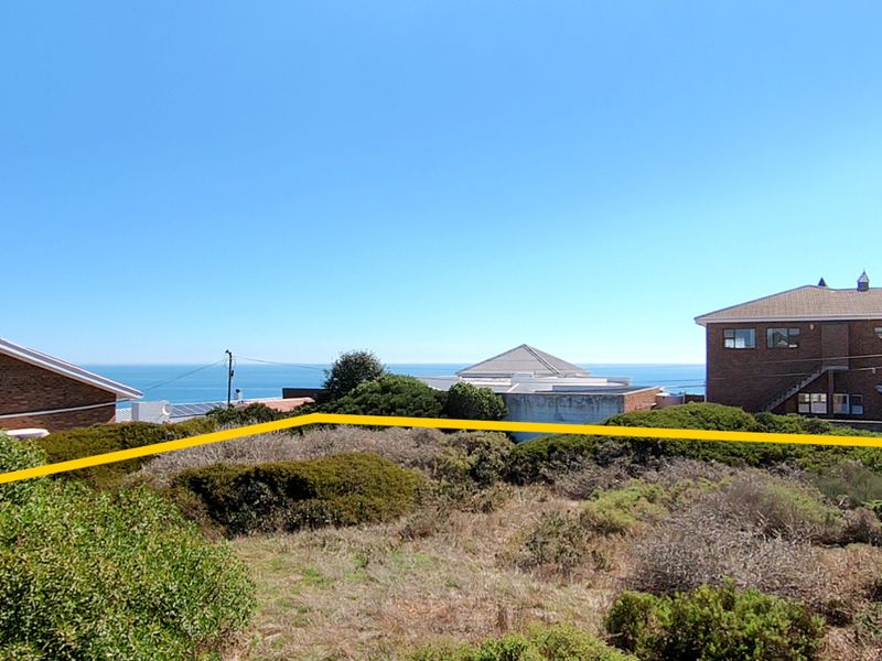 A vacant residential plot featuring coastal views, surrounded by established residential properties and natural coastal vegetation.
