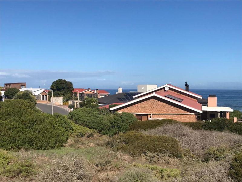An elevated view of the residential neighborhood and coastal landscape, showcasing the surrounding properties and proximity to the ocean.