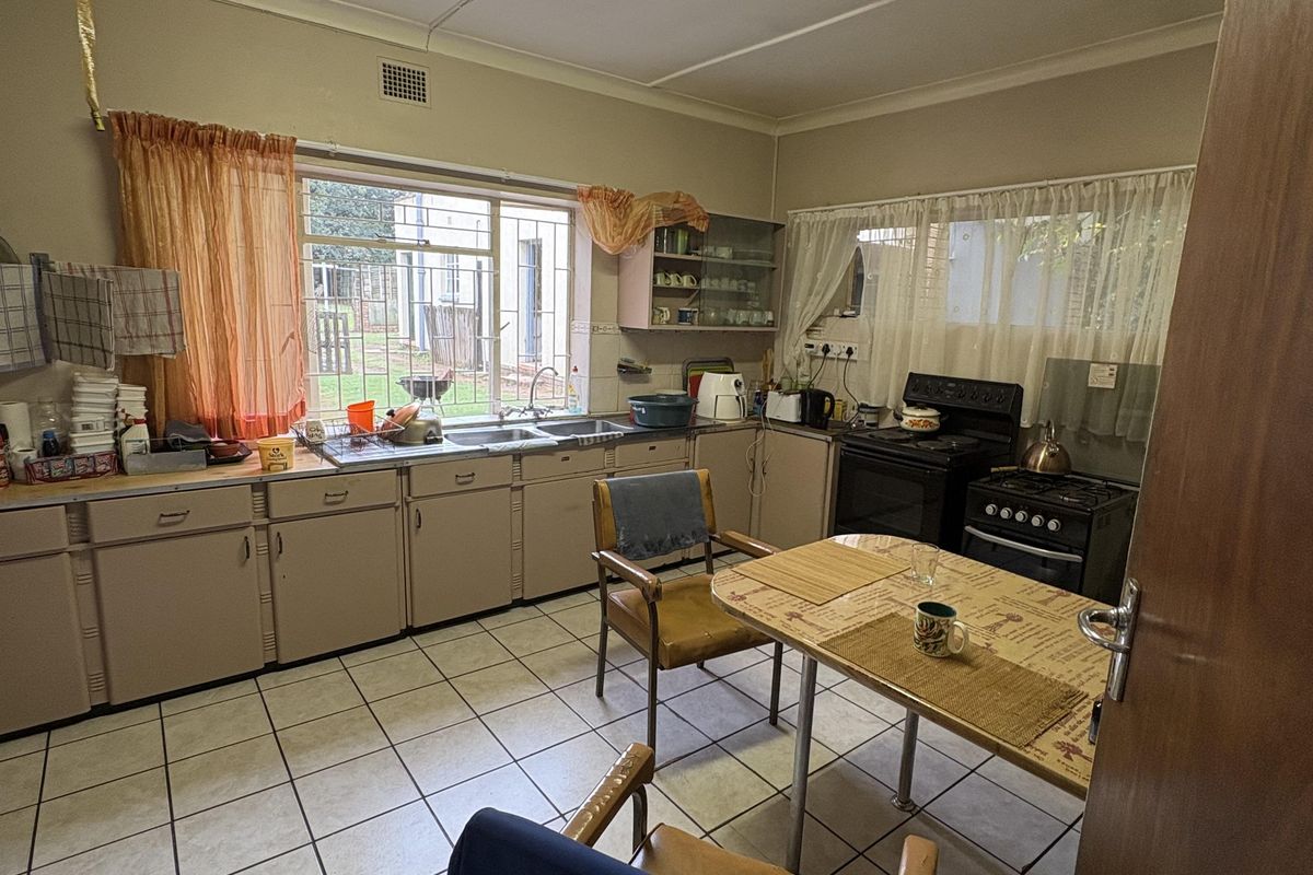 A functional kitchen featuring original cabinetry, tiled flooring, and a freestanding stove, offering potential for a modern renovation.