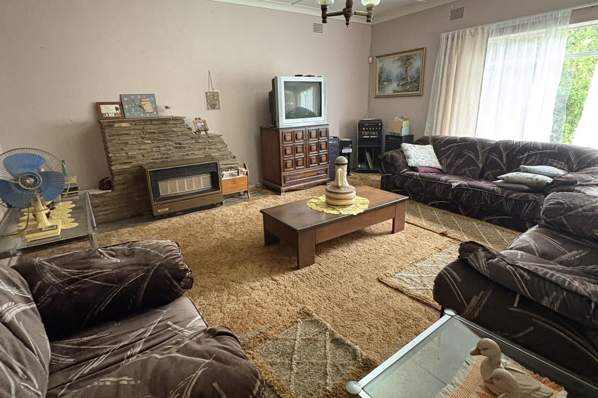 Spacious living room featuring a stone-clad fireplace, large windows for natural light, and carpeted flooring.
