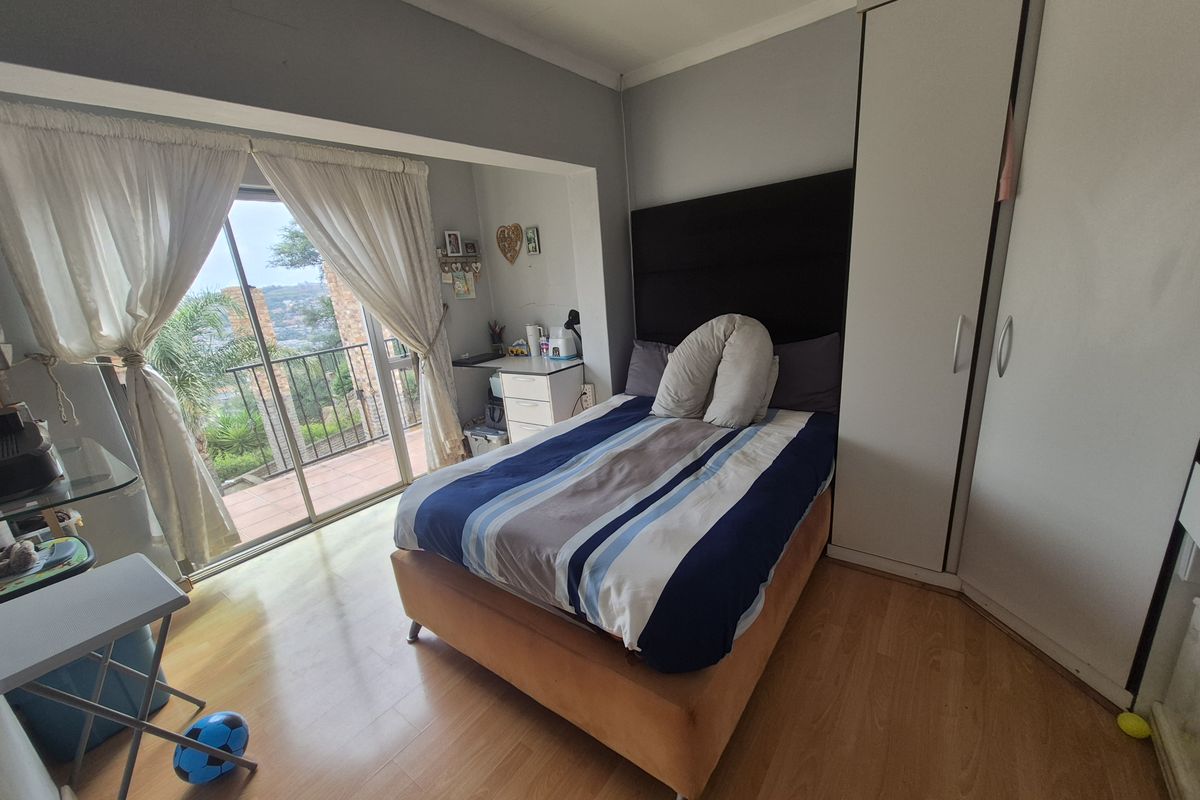A bedroom featuring laminate flooring, built-in wardrobe, and sliding glass doors opening onto a balcony with scenic views.
