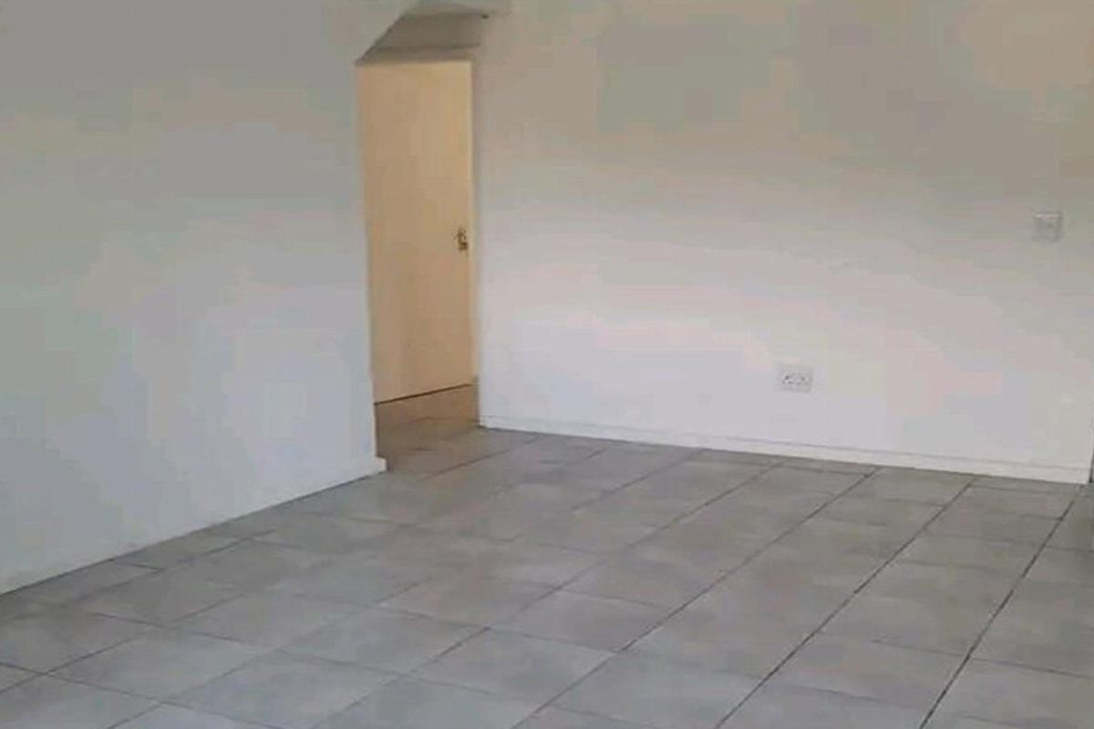 An empty living area featuring neutral tiled flooring and plain walls, providing a blank canvas for interior design.