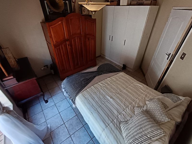 A bedroom featuring tiled flooring and a built-in wardrobe, providing functional storage space.