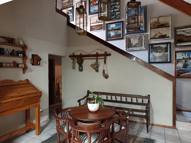 A living area featuring a staircase with wooden trim and tiled flooring, providing a functional space with potential for modern updates.