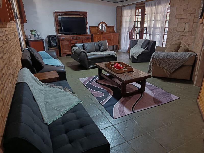 Spacious living room featuring exposed brick walls, tiled flooring, and large glass french doors providing natural light.