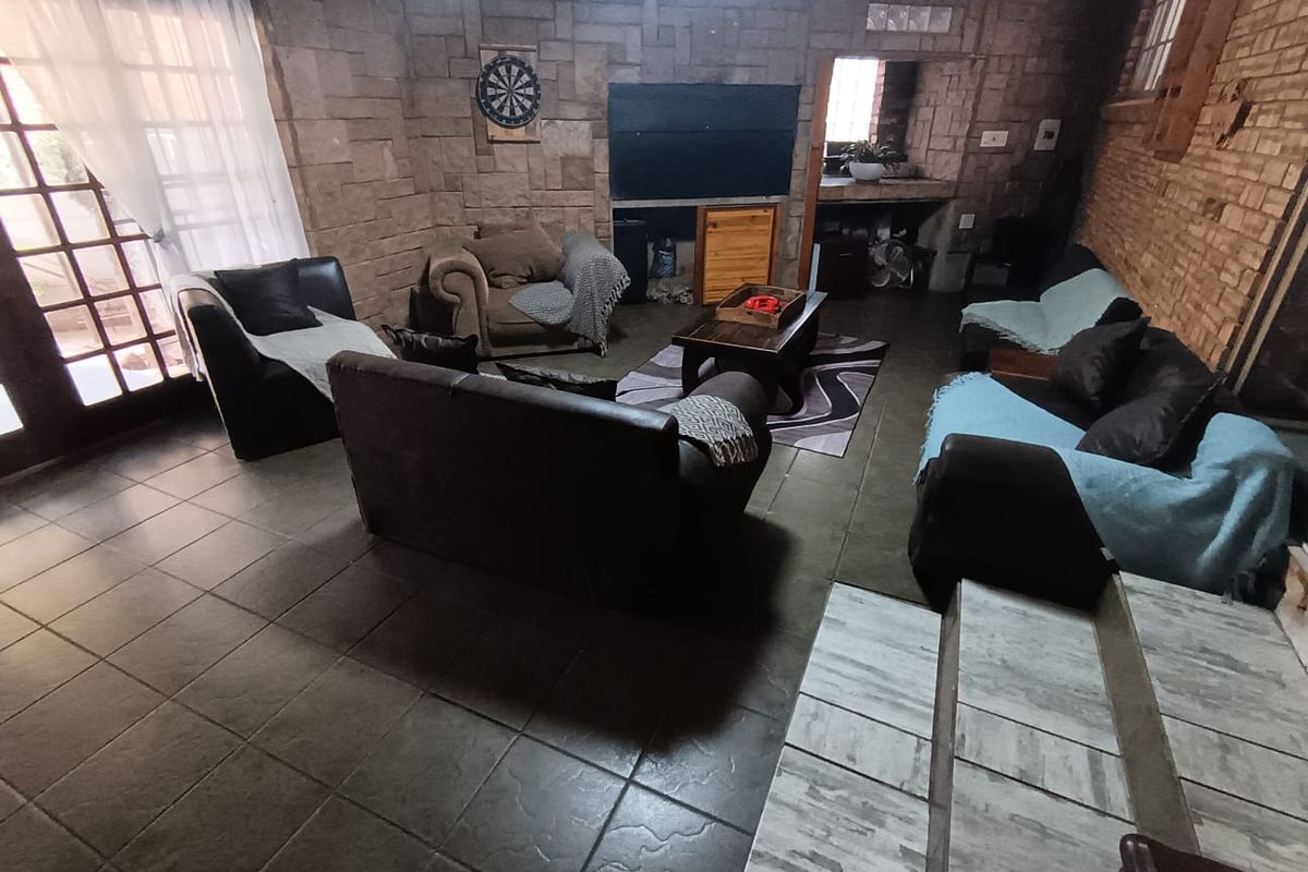 Spacious living area featuring rustic stone and brick wall finishes, tiled flooring, and direct access to the exterior through french doors.