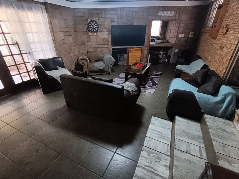 Spacious living area featuring rustic stone and brick wall finishes, tiled flooring, and direct access to the exterior through french doors.