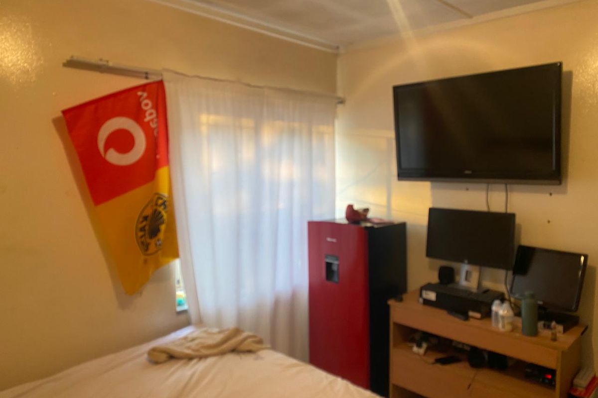 A bedroom featuring a wall-mounted television and a curtain rail, providing a functional space for rest and entertainment.
