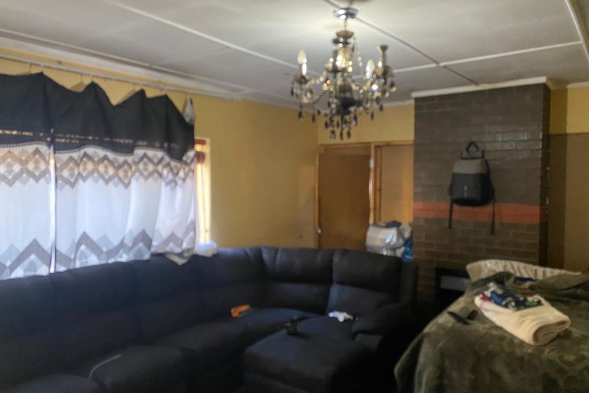 Living room featuring a brick fireplace, decorative chandelier, and tiled ceiling. The space requires cosmetic updates to modernize the interior finishes.
