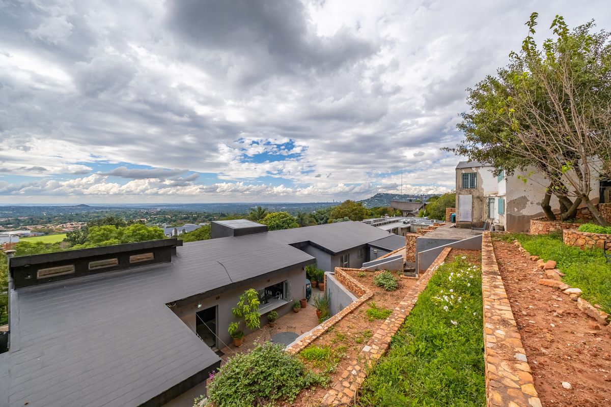 Aerial view of a property featuring terraced stone gardens, a flat-roofed structure with a serving window, and expansive views of the surrounding landscape.