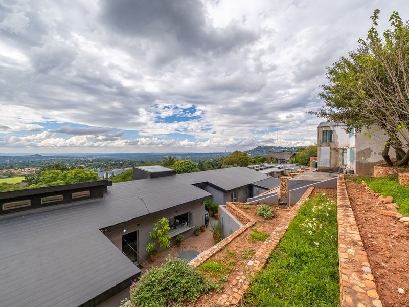 Aerial view of a property featuring terraced stone gardens, a flat-roofed structure with a serving window, and expansive views of the surrounding landscape.