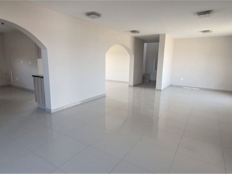Spacious open-plan living area featuring polished tile flooring, arched transitions, and a modern kitchen with built-in oven and extractor fan.