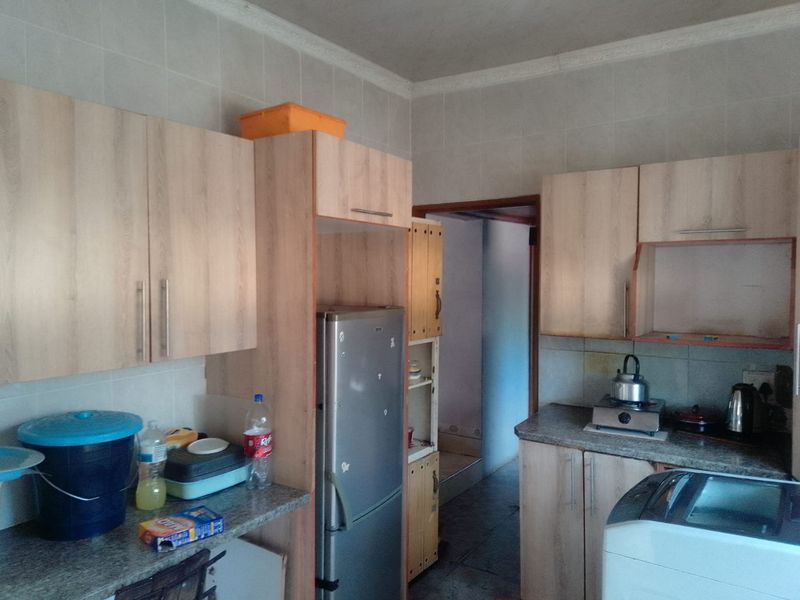 A functional kitchen featuring light wood-tone laminate cabinetry, granite countertops, and tiled wall finishes, offering a practical layout for daily meal preparation.