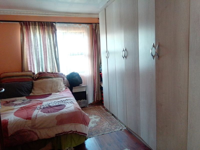 A bedroom featuring built-in cupboards, laminate flooring, and decorative ceiling cornice.