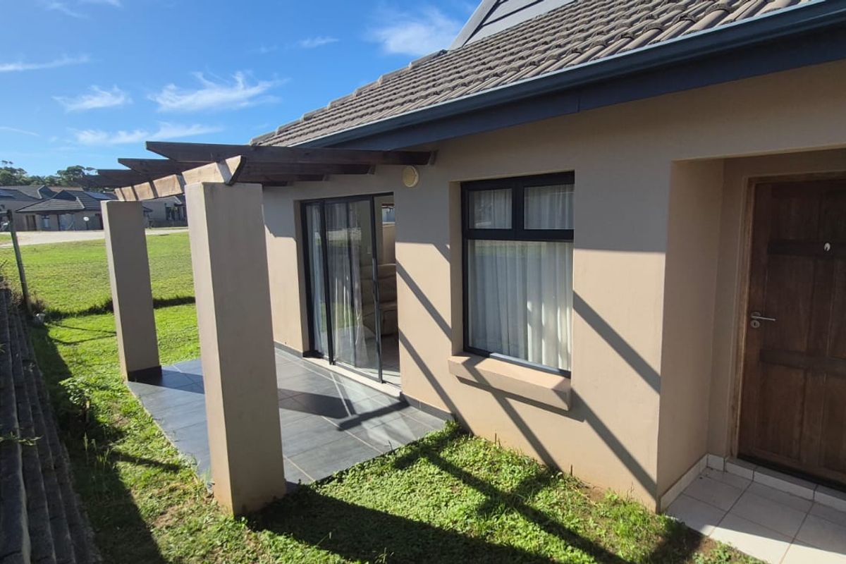 Rear exterior view featuring a tiled patio with a timber pergola, sliding glass door access, and a well-maintained tiled roof structure.