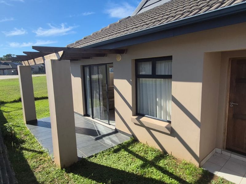 Rear exterior view featuring a tiled patio with a timber pergola, sliding glass door access, and a well-maintained tiled roof structure.