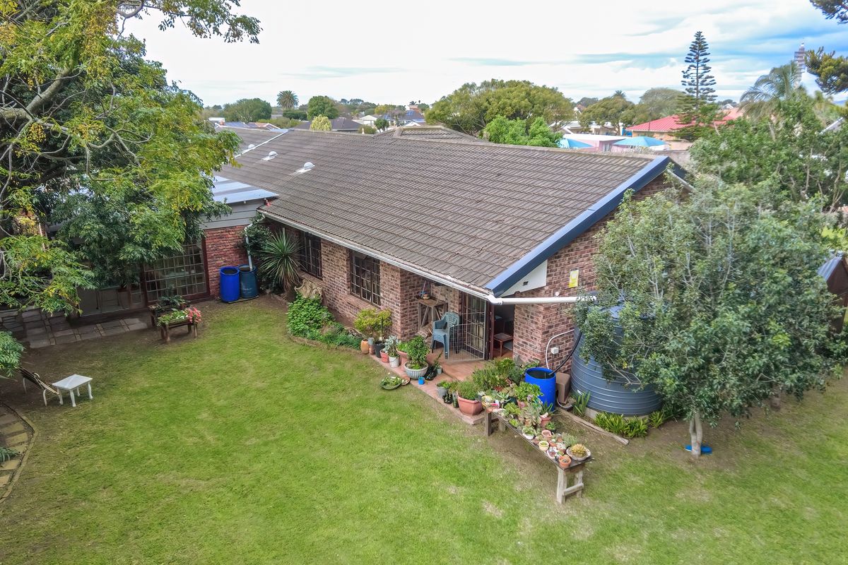 Aerial view of the property showing the rear brick facade, tiled roof, and surrounding garden space with a rainwater collection system.