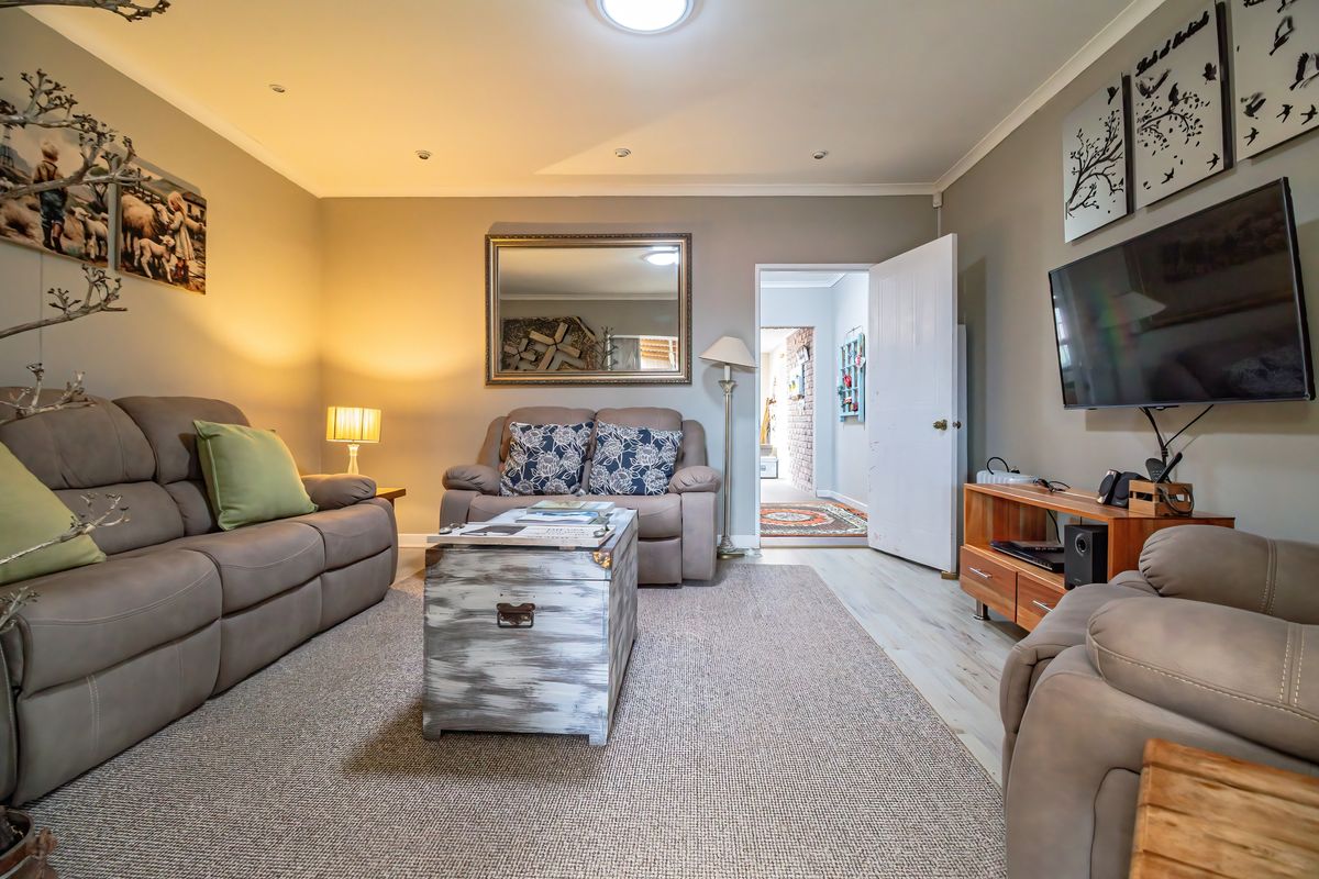 A comfortable living room featuring recessed downlighting, coving, and neutral wall finishes, providing a warm and inviting space for relaxation.