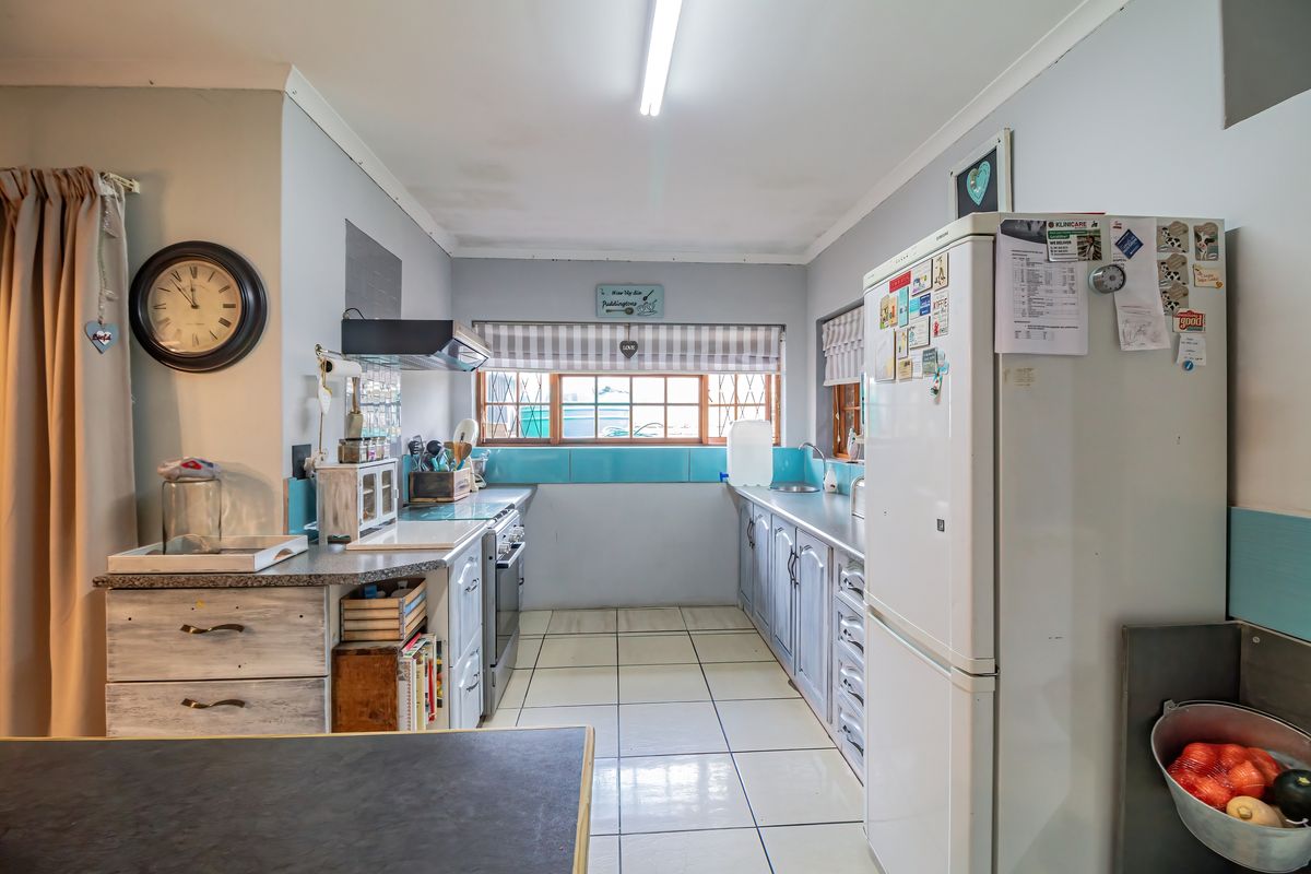 A functional kitchen featuring tiled flooring, built-in cabinetry, a stove with an extractor fan, and a tiled backsplash.