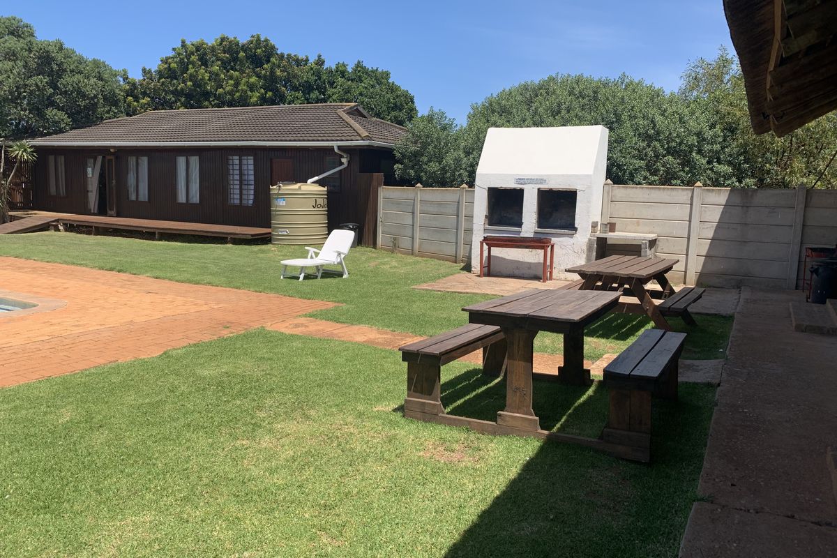 Spacious outdoor area featuring a built-in braai, lawn, and paved sections, providing a functional space for outdoor entertaining and relaxation.
