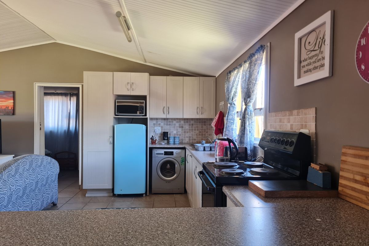 A functional kitchen area featuring built-in cabinetry, a tiled backsplash, a stove, and an integrated laundry space with a washing machine.