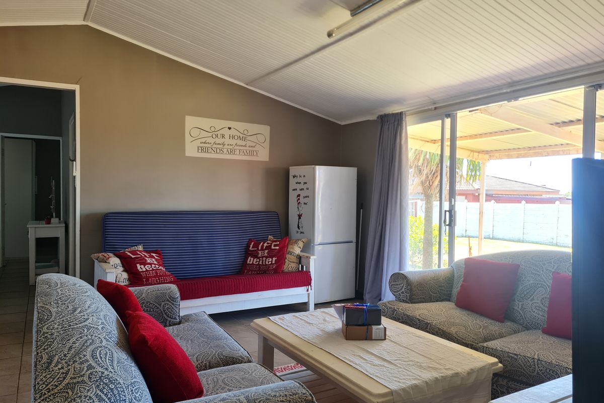 A comfortable living room featuring a sloped ceiling and large sliding glass doors that provide direct access to the outdoor patio area.
