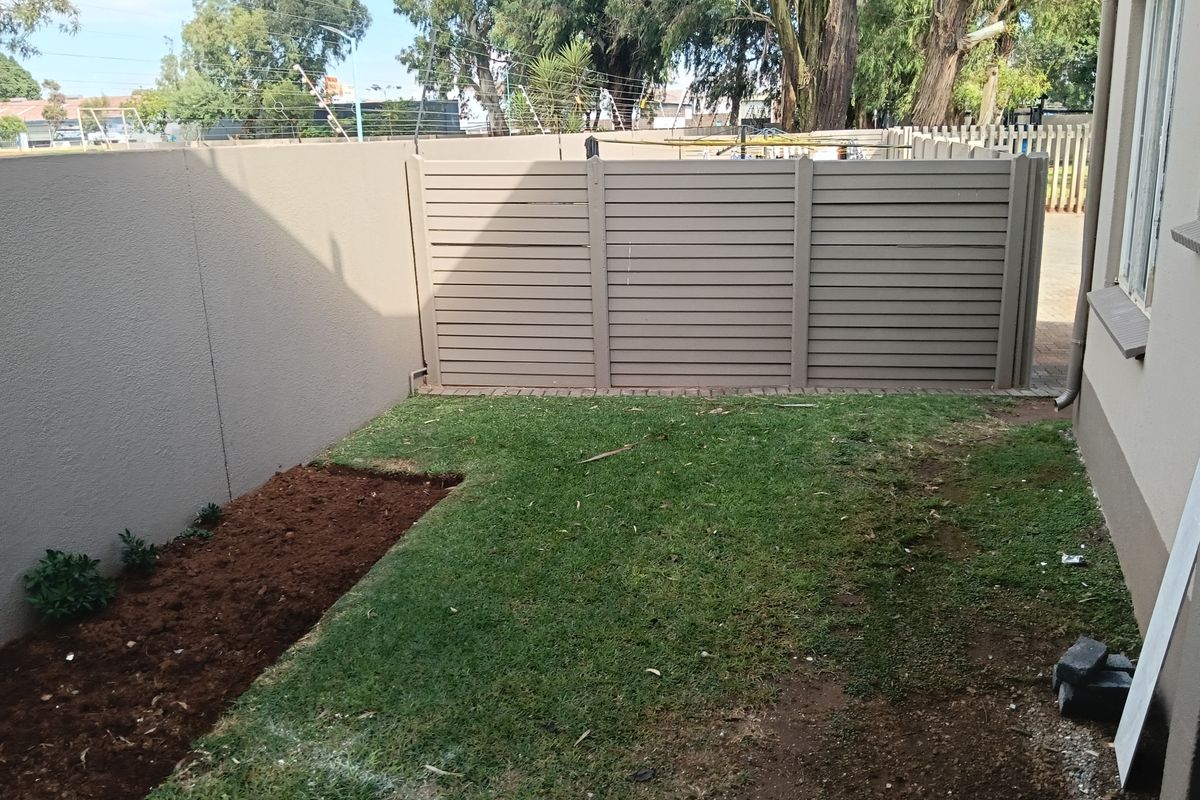 A private rear garden area featuring a lawn, a small garden bed, and a modern horizontal slat privacy fence.