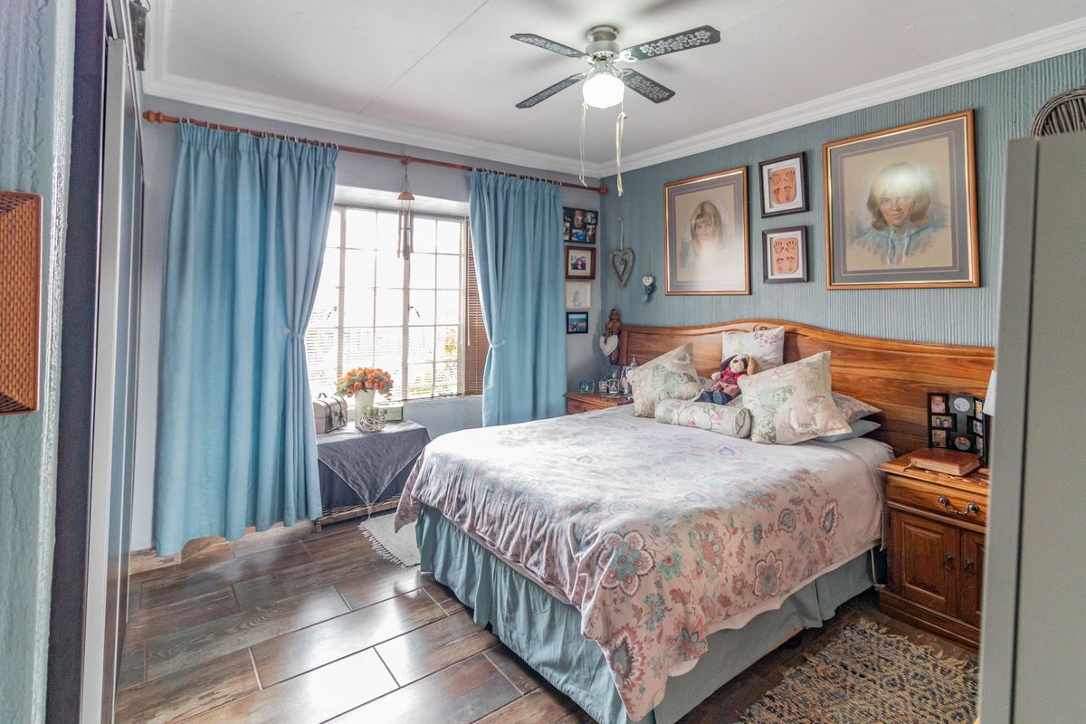 A well-maintained bedroom featuring tiled flooring, a ceiling fan, and built-in wardrobe storage, offering a comfortable and functional living space.