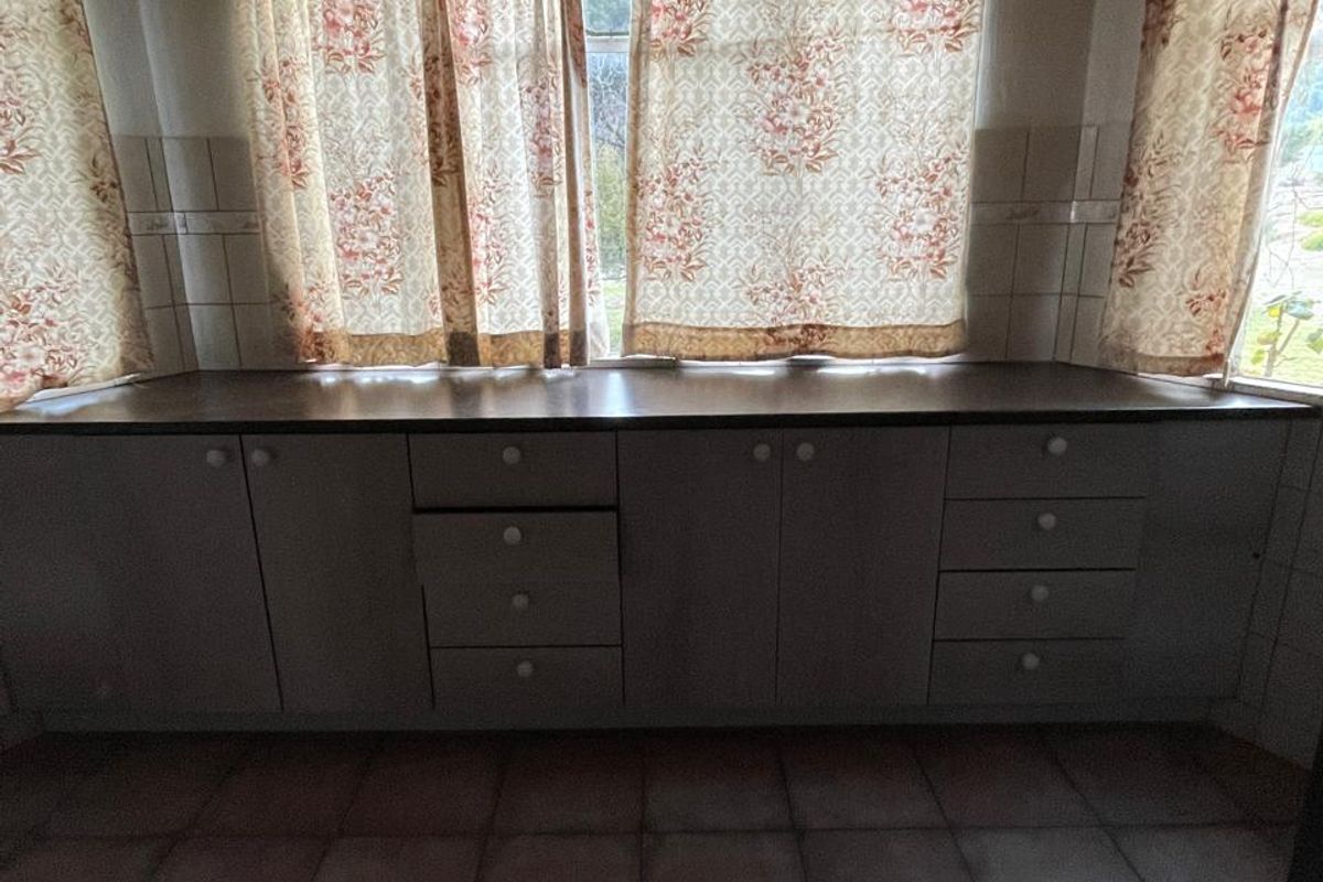 A kitchen area featuring built-in cabinetry with a countertop, tiled flooring, and a bay window configuration.