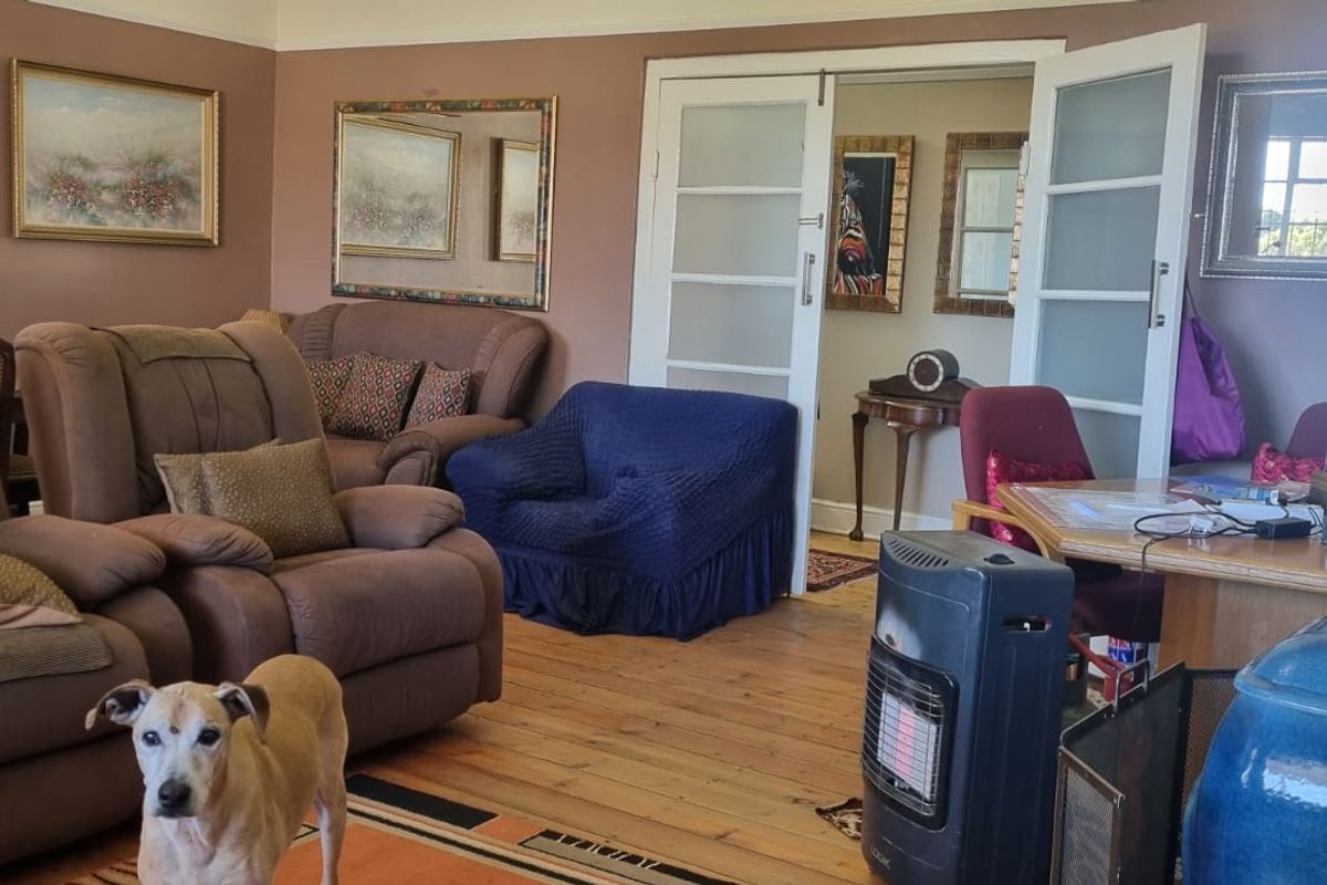 A spacious living room featuring original timber flooring, a built-in fireplace, and double glass-panelled doors leading to an adjacent room.