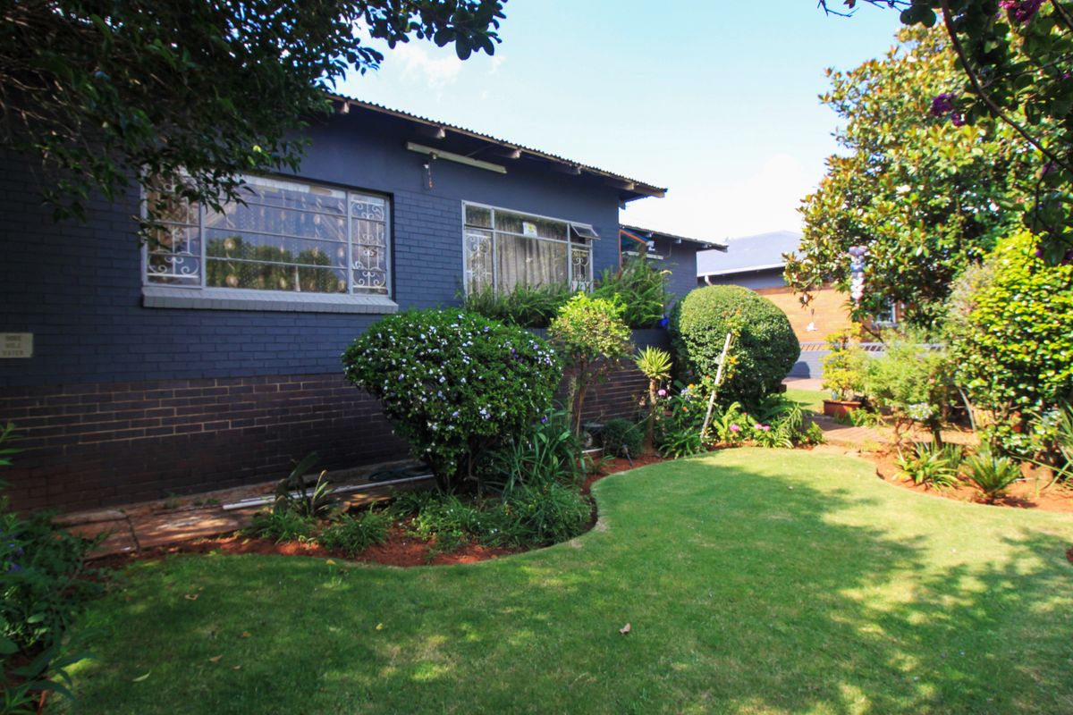 A view of the rear exterior of the house featuring a painted brick facade, steel-framed windows, and a well-maintained garden area.