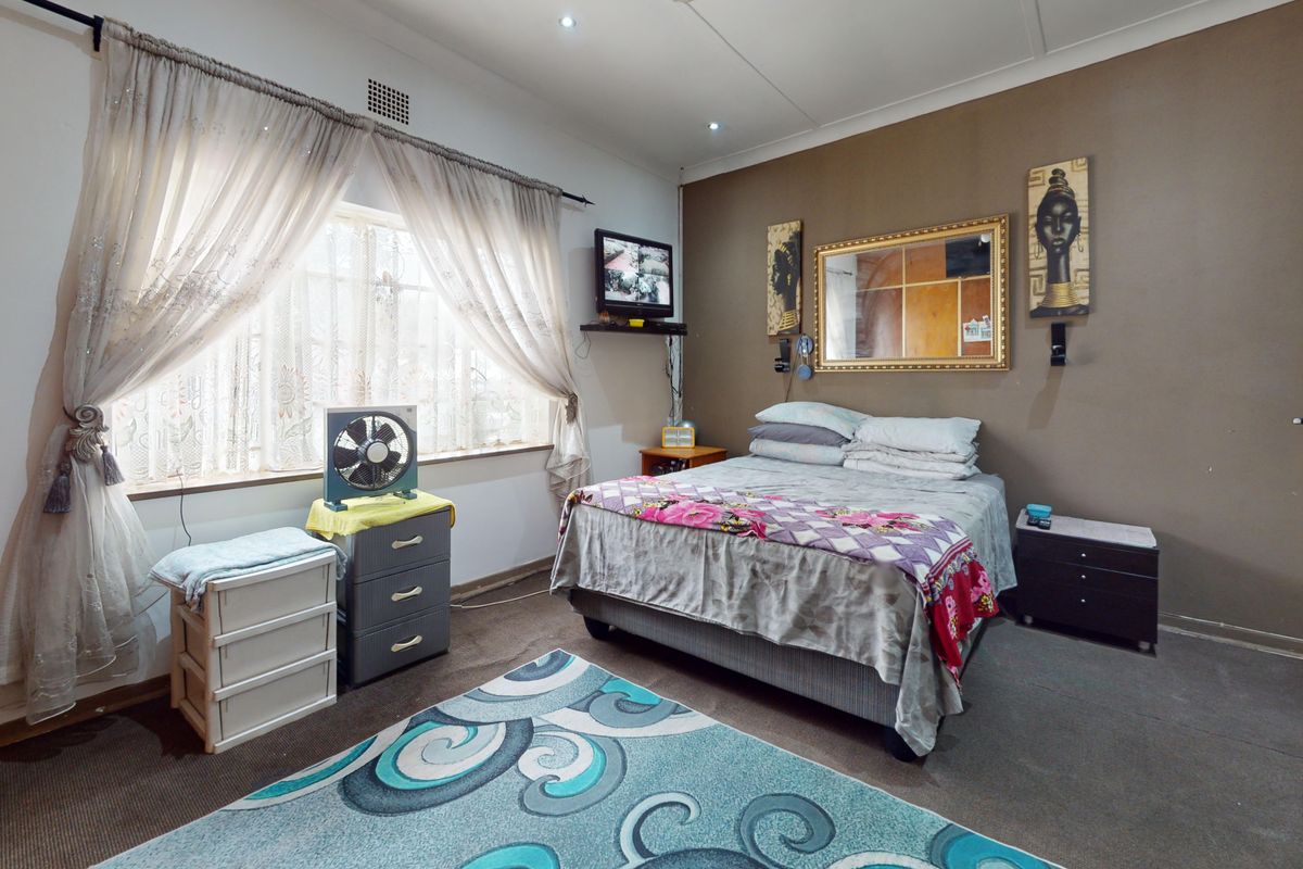 A functional bedroom featuring neutral wall tones, carpeted flooring, and recessed lighting, offering a comfortable space with potential for modern updates.