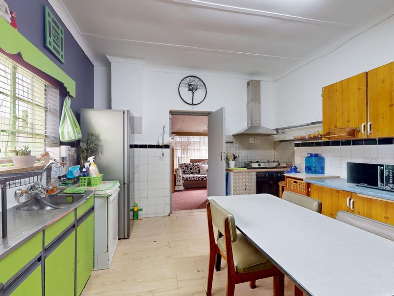 A functional kitchen featuring built-in cabinetry, a gas hob with extractor fan, and tiled splashbacks, offering potential for a modern renovation.