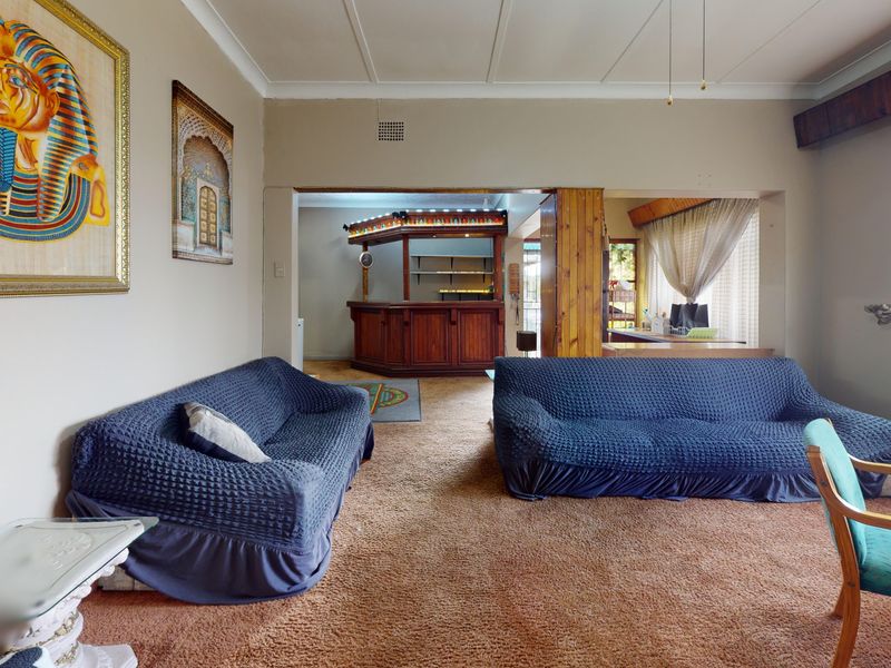 Spacious living area featuring a built-in bar, neutral wall tones, and large windows with security gates, offering a versatile layout for entertaining.