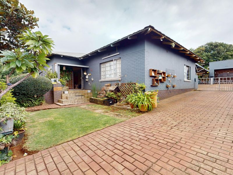 Front view of a single-story house featuring a brick driveway, tiled entrance steps, and a detached garage.