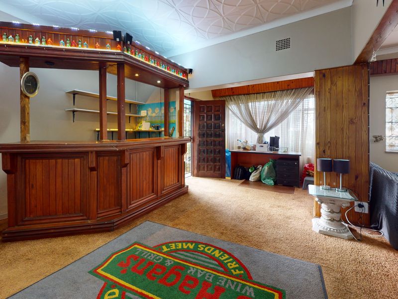 A dedicated bar area featuring a built-in wooden counter, shelving, and decorative ceiling, offering a classic entertainment space with potential for modernization.