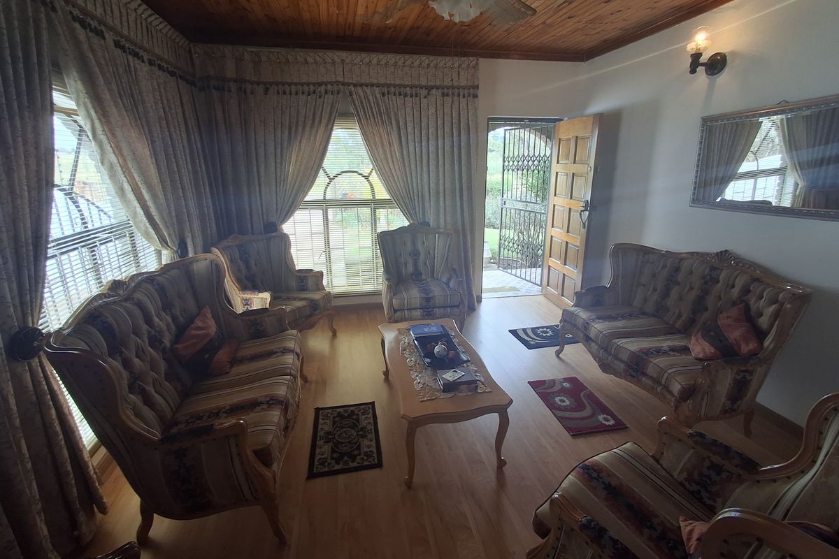 A traditional living room featuring a warm timber ceiling, laminate flooring, and direct access to the exterior through a security gate.