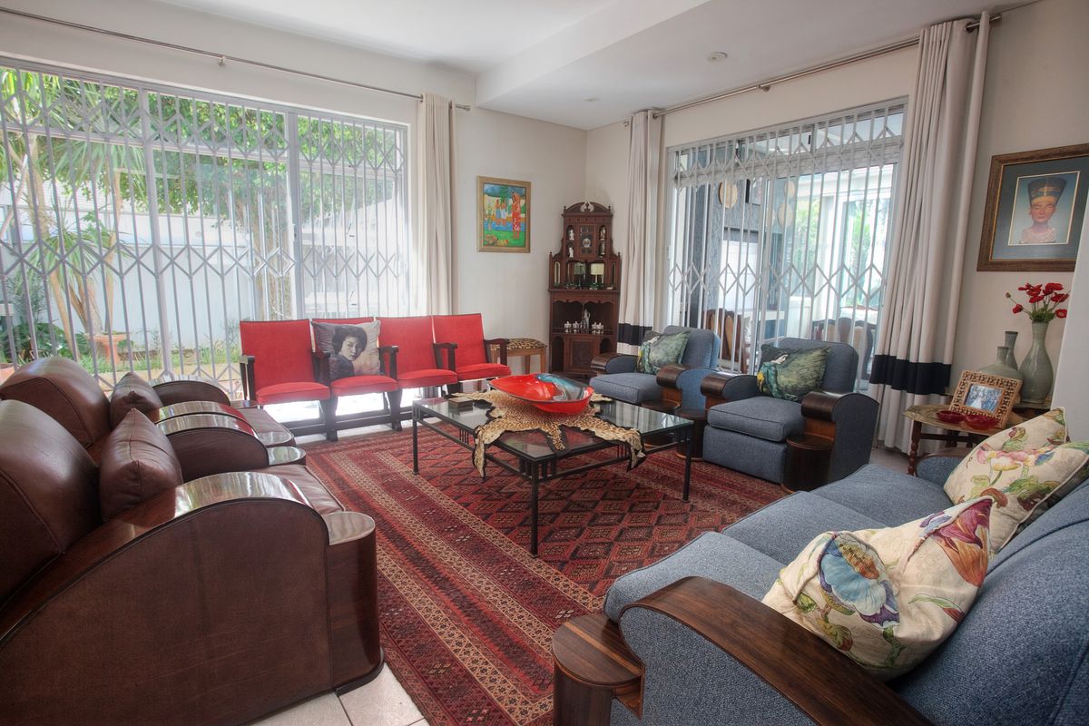 Spacious living room featuring large sliding glass doors with security gates, recessed ceiling lighting, and neutral tiled flooring.