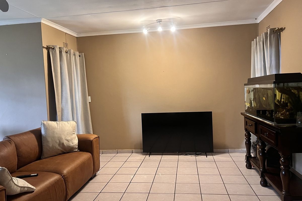 A living room featuring tiled flooring, neutral wall paint, and a ceiling fan, providing a functional and versatile space for relaxation.
