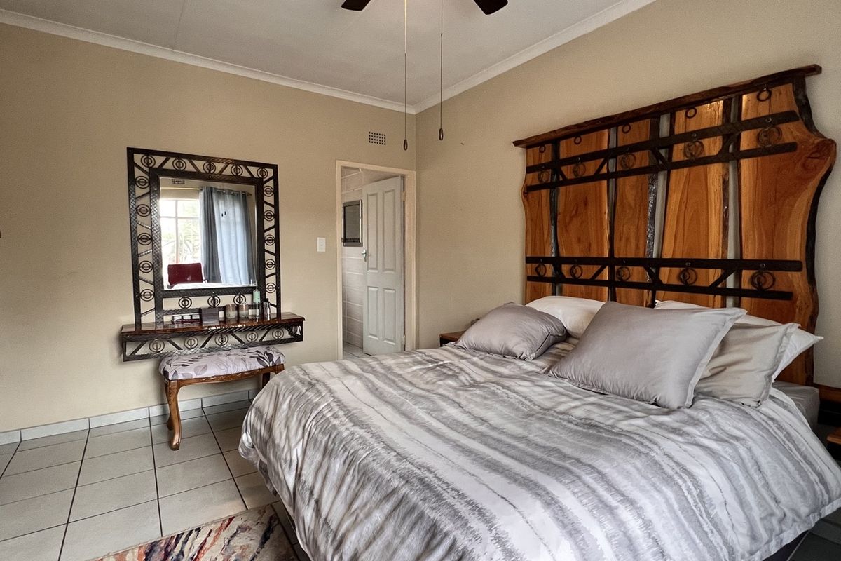 A well-maintained bedroom featuring tiled flooring, a ceiling fan, and a built-in vanity area with an attached mirror.