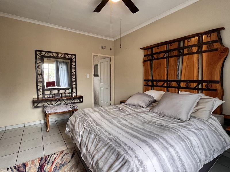 A well-maintained bedroom featuring tiled flooring, a ceiling fan, and a built-in vanity area with an attached mirror.