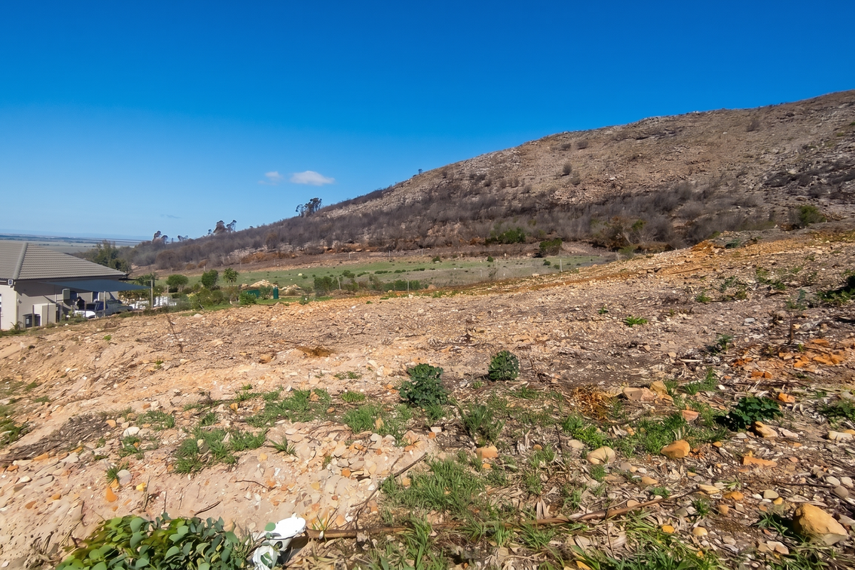 A wide-angle view of the vacant residential land featuring a natural sloped terrain with scenic mountain views in the background.