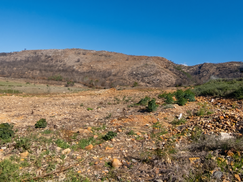 A wide-angle view of the vacant residential land featuring natural rocky terrain and scenic mountain vistas in the background.