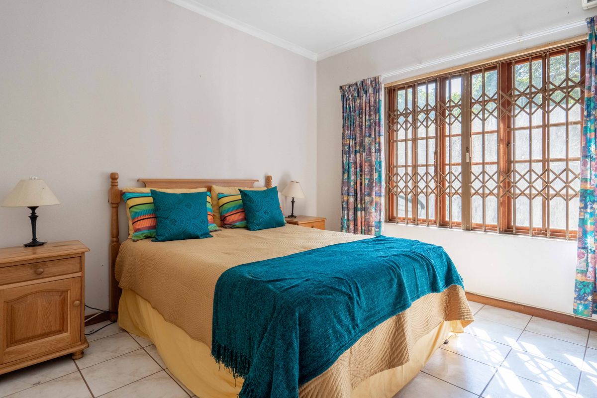 A bedroom featuring tiled flooring and a window fitted with a security gate.