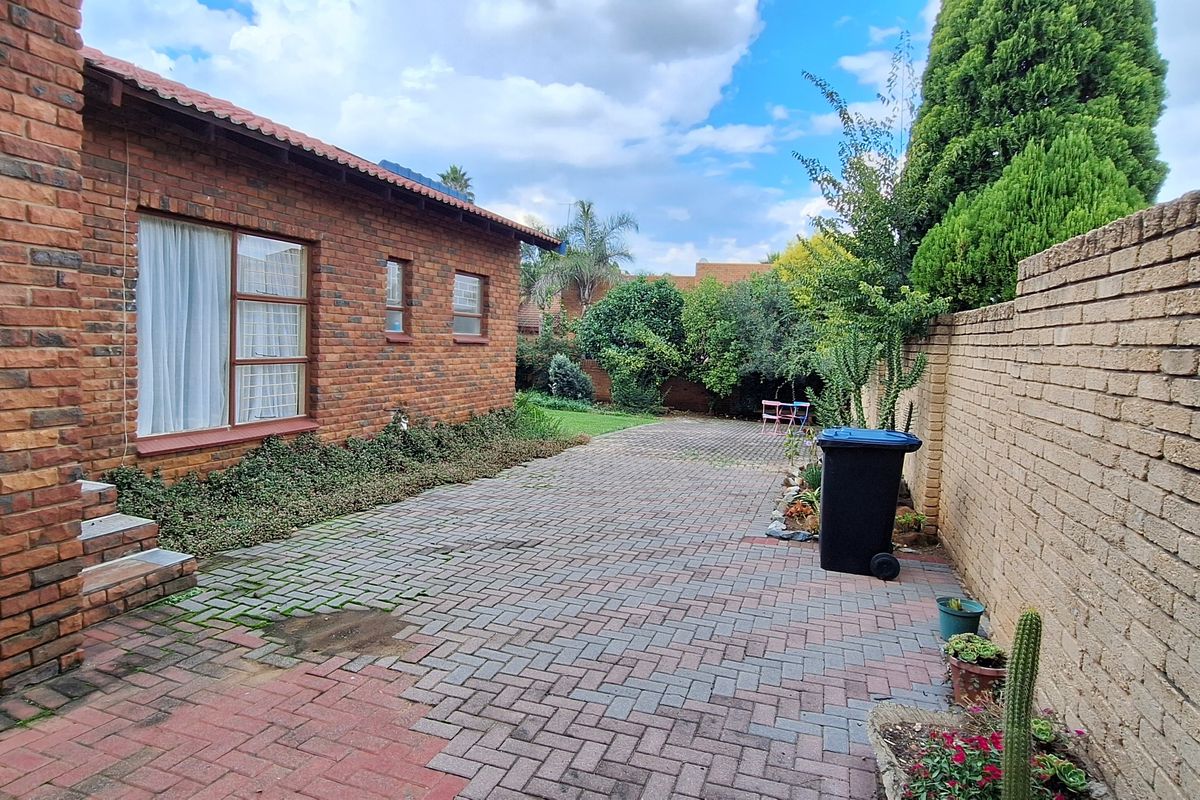 A private rear courtyard featuring brick paving, established garden borders, and a perimeter brick boundary wall.