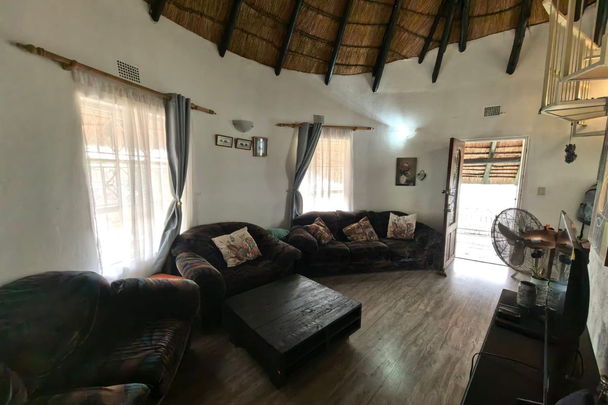 A circular living room featuring a traditional thatched roof with exposed timber rafters and durable laminate flooring, offering a unique architectural aesthetic.