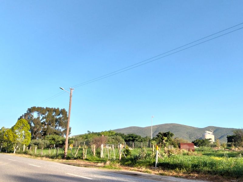A street-level view of the vacant residential land, featuring existing wire fencing, utility infrastructure, and scenic mountain views in the background.